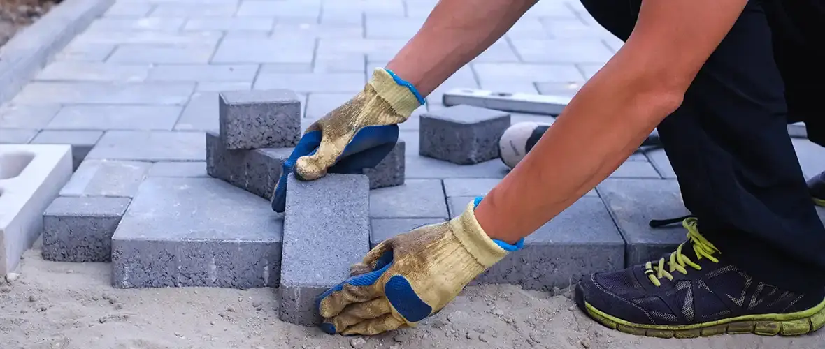 Worker laying and maintaining concrete paving slabs in Washington’s wet climate for long-lasting durability.